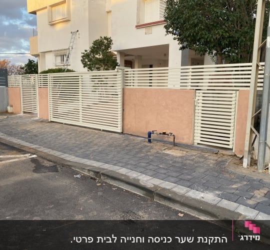 גדר מתכת לבנה ליד בית עם מדרכה מרוצפת